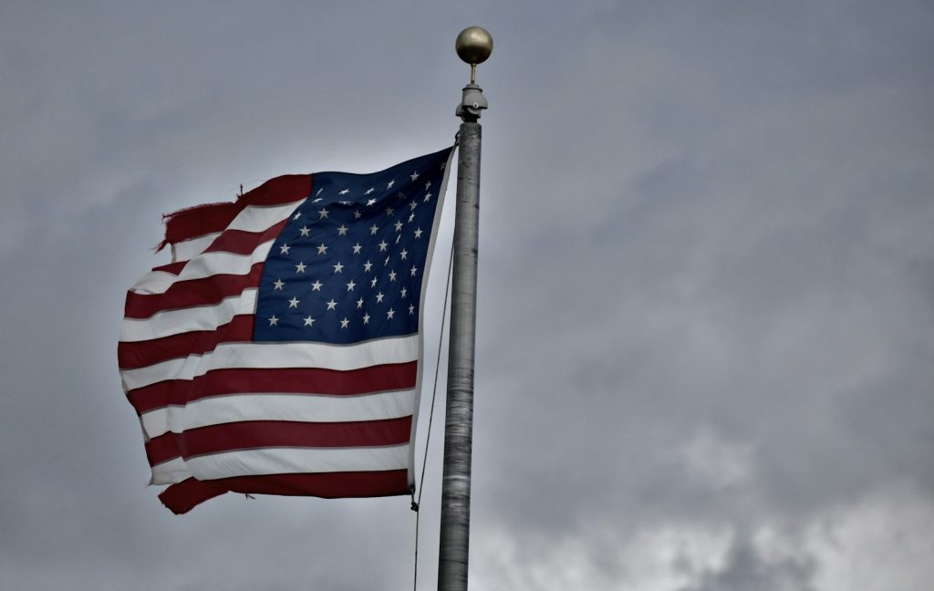 an american flag flying in the wind on a cloudy day